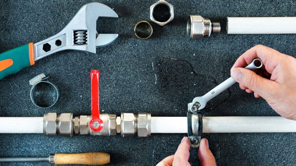 Plumber repairing a pipe valve with an adjustable wrench in Haines City