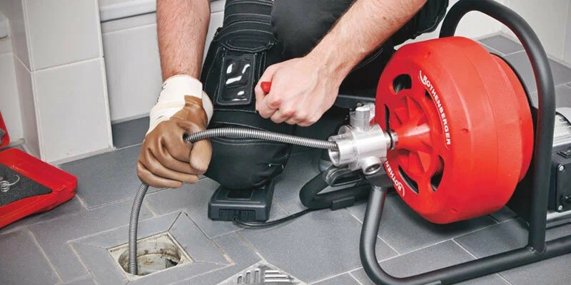 Plumber using a drain-cleaning machine in Haines City