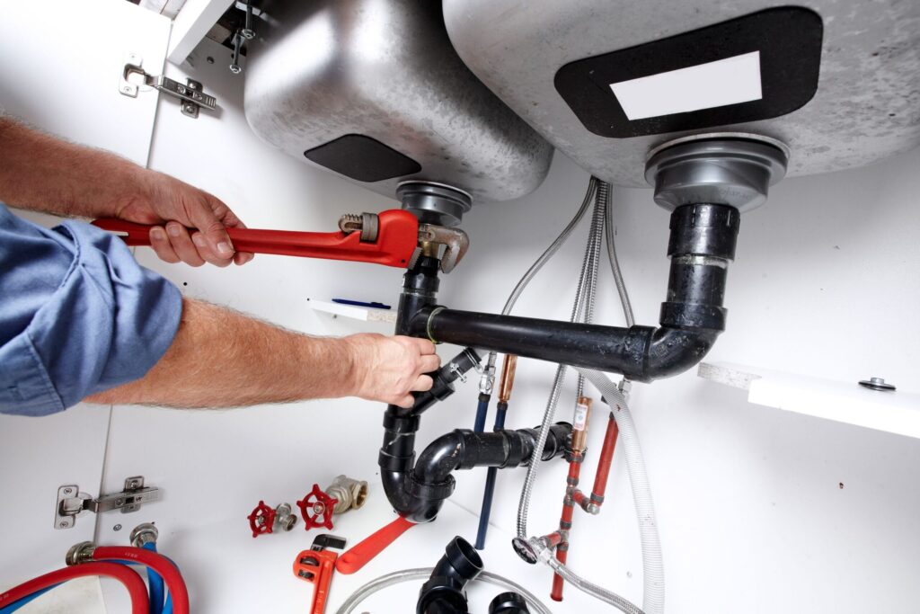 Plumber repairing drain pipes beneath a kitchen sink in Haines City
