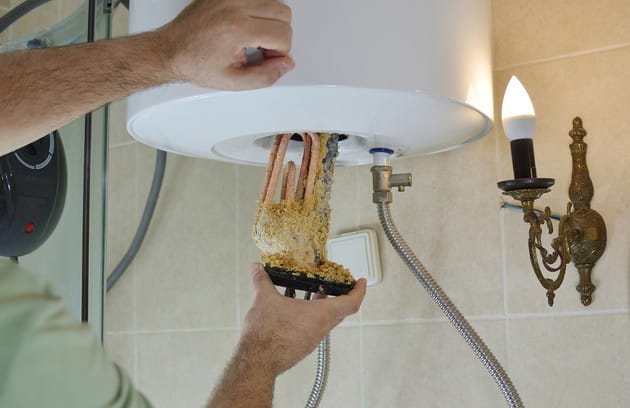 Technician removing mineral buildup from a water heater in Haines City