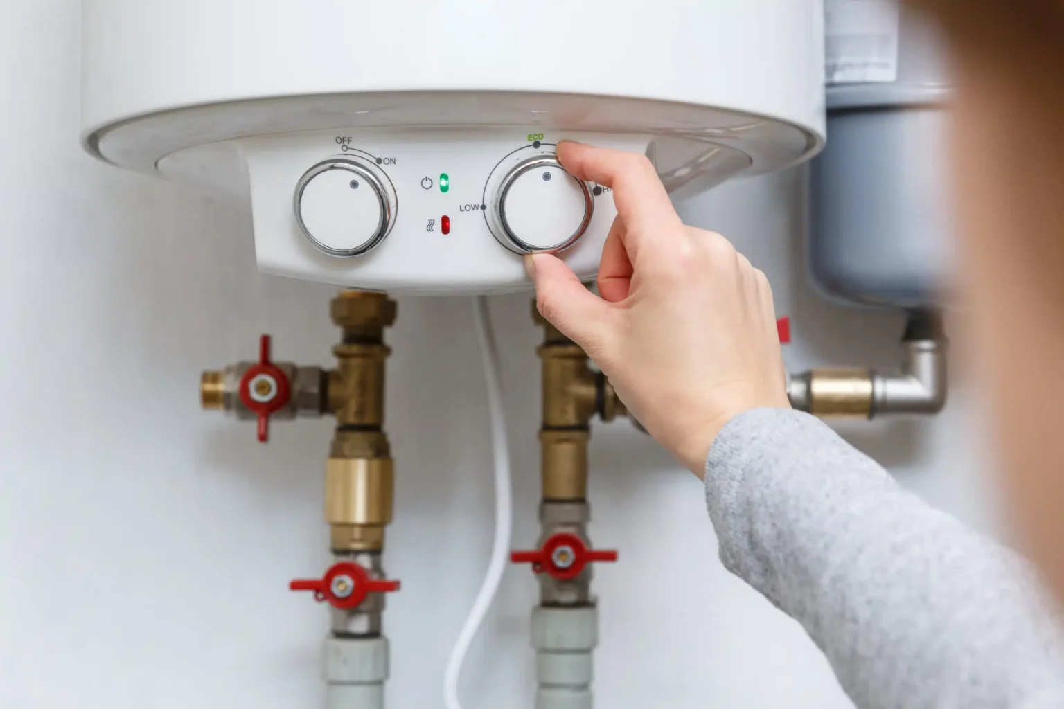 Homeowner adjusting the temperature controls on a water heater in Haines City